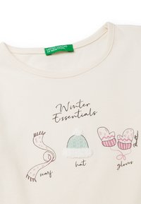 Krémová košile se tištěnými ilustracemi šály, klobouku a rukavic označenými jako "Zimní nezbytnosti", s pastelovými barvami a jemnými texturami.