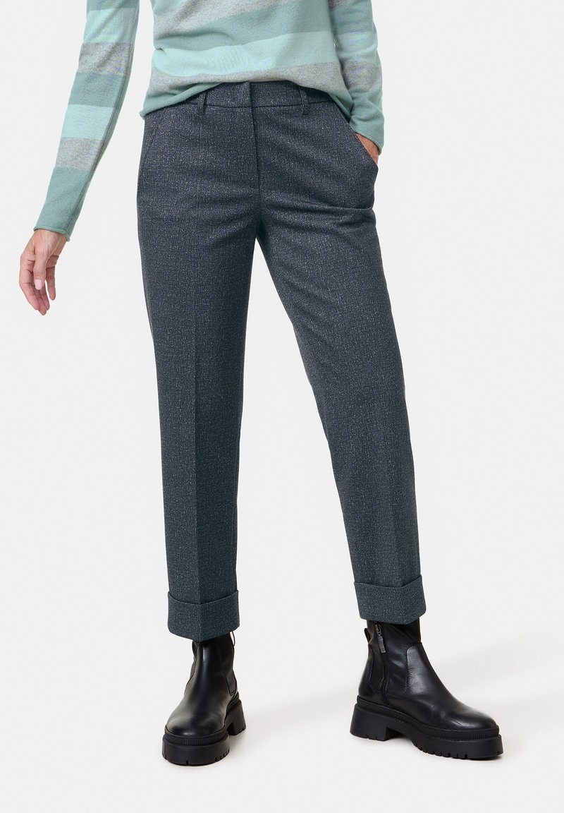 Pantalons texturés gris avec une coupe ajustée, ourlet à revers, poches latérales, associés à des bottines noires hauteur de cheville.