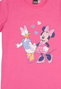 Maglietta rosa con Minnie Mouse in un vestito rosa a pois che tiene per mano Paperina, che indossa una maglietta blu, circondate da tre cuori.