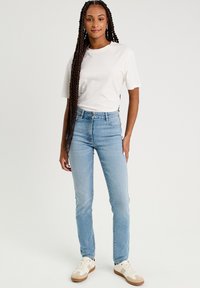 Lyseblå højtaljede jeans lavet af denim, med knaplukning og femlomme desig. Sæt sammen med en hvid t-shirt med korteærmer og sneakers.