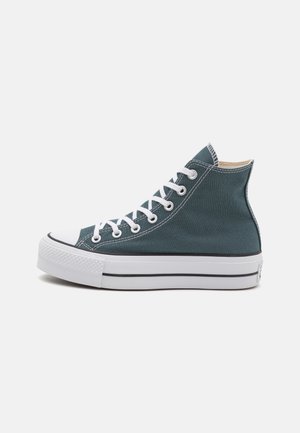 Sneakers alte in tela di colore verde scuro con lacci bianchi. Dotati di punta in gomma, suola bianca con strisce nere e dettagli cuciti.