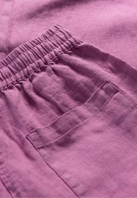 Violets lins Dienestaudums ar savilktu elastīgu jostu un sānu kabatu detaļām. Auduma tekstūra izskatās mīksta un nedaudz burzīta.