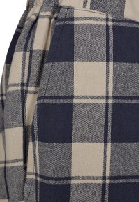 Brændt stof med beige og marineblå tern med skiftevis striber. Materialet fremstår tekstureret med en blød overflade.