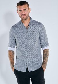 Kurzarm-Hemd in Dunkelblau mit geometrischem Muster, kontrastierenden weißen Manschetten und einem Logodetail auf der Brust.