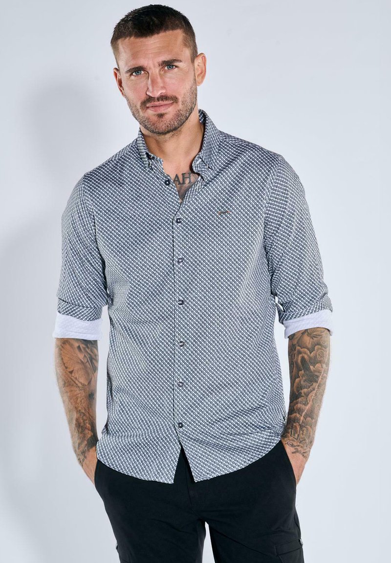 Kurzarm-Hemd in Dunkelblau mit geometrischem Muster, kontrastierenden weißen Manschetten und einem Logodetail auf der Brust.