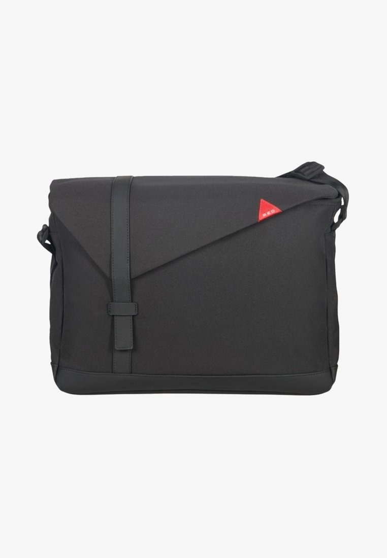 Musta viestintälaukku, jossa on teksturoitu kangasrunko, viisto läppäkiinnitys ja punainen kolmionmuotoinen logoakseli. Säädettävä olkahihna mukana.