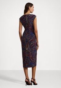 Rochie mulicolor cu imprimeu paisley, într-un design ajustat. Fără mâneci, până la genunchi, cu fermoar la spate, având un amestec de nuanțe de albastru, roșu și auriu.