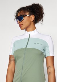 Zöld és fehér kerékpáros mez cipzárral. Jellemzője a tompított árnyalatokban készült színblokk design, valamint a Vaude logó elöl.
