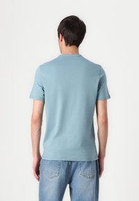 T-shirt in cotone blu chiaro con maniche corte, colletto rotondo e una texture liscia. Presenta cuciture pulite senza loghi o motivi visibili.