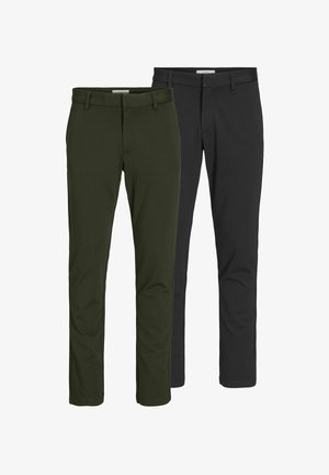 Olíva zöld, testre szabott öltöny, hozzá illő nadrággal, világosbarna pulóverre húzva; sima fekete cipőkkel és minimalista dizájnnal rendelkezik.