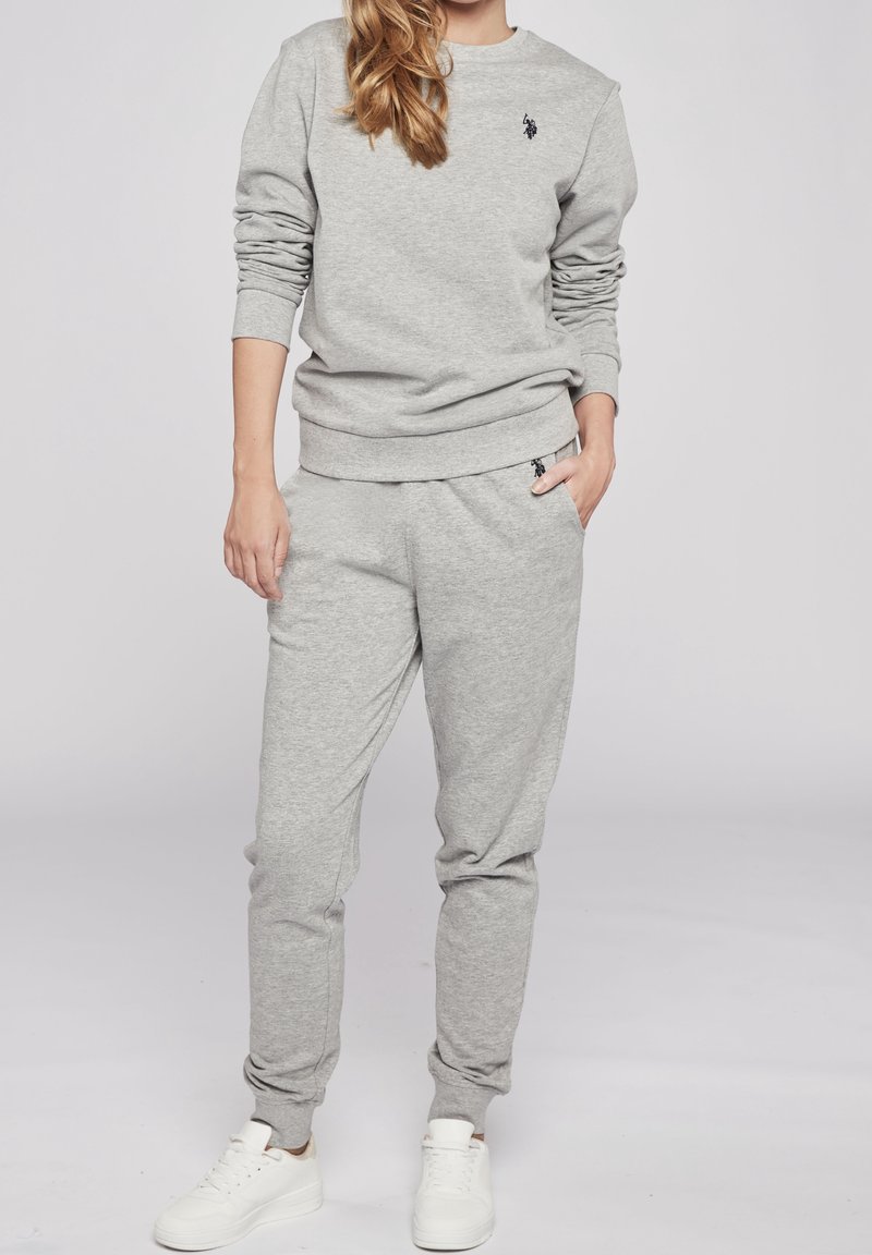 Grå sweatshirt och sweatpants i mjukt material, med ribbat avslut. Litet logotypdetalj på bröstet och höften. Matchas med vita sneakers.