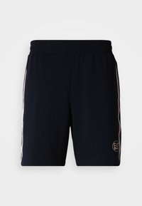 Námornícky modré športové šortky z mäkkej látky s elastickým pásom, bielymi bočnými pruhmi a okrúhlym logom na dolnej pravej strane.