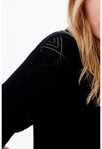 Schwarzer Strickpullover mit strukturierten Mustern an den Schultern, elegantem Design und leichter Transparenz in den Nahtdetails.