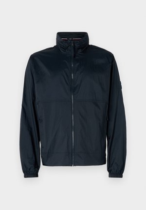 Tengerészkék szélálló dzseki, könnyű anyagból, cipzáros rögzítéssel, magas gallérral, rugalmas mandzsettákkal és finom textúrával.