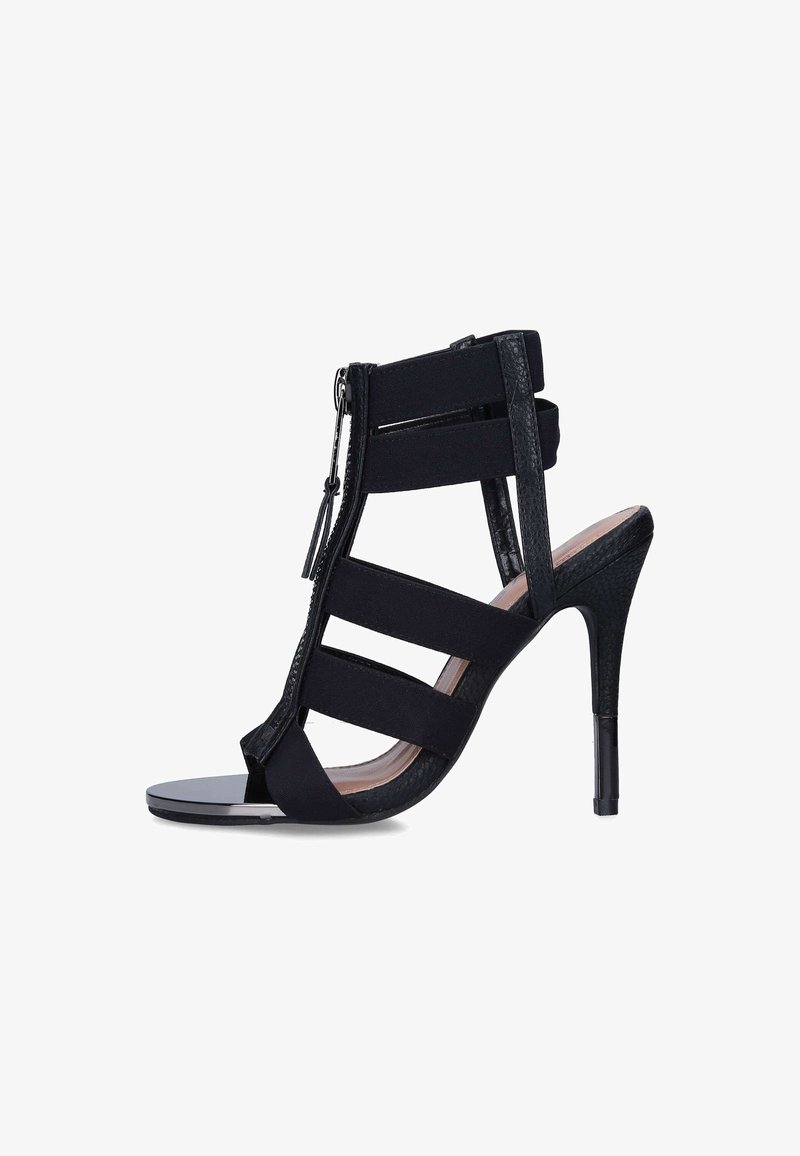 Sandale noire à talon haut avec plusieurs brides élastiques, bout ouvert et fermeture éclair à l'avant, vue de profil sur fond blanc.