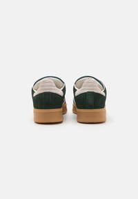 Green suede sneakers featuring a beige padded collar and a gum outsole. Rounded shape with visible stitching detail at the heel.