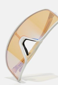 Lunettes de sport avec une monture blanche et des verres teintés orange. Elles présentent un design courbé et un accent noir sur le nez.