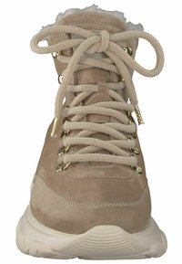 Beige semišové kotníkové boty s kožešinovou podšívkou, zlatými očky, silnými šňůrkami a robustní bílou podrážkou. Frontal view, ukazující detaily šněrování.
