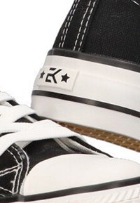 Zapatillas altas de lona negra con suela de goma blanca, cordones blancos y un logo con estrellas y una letra en el panel lateral.