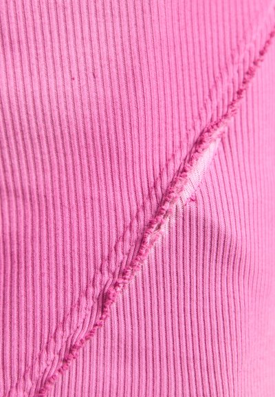Rosa geripptes Material mit einer auffälligen Nahtdetail. Die strukturierte Oberfläche zeigt horizontale Linien und ein unregelmäßiges Stichmuster.