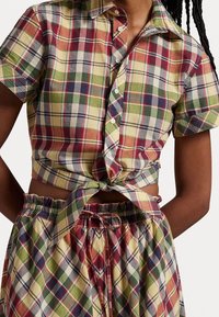 Short-sleeve plaid shirt in yellow, red, green, and blue; tied at the waist with button closure. Coordinating plaid shorts with elastic waistband.