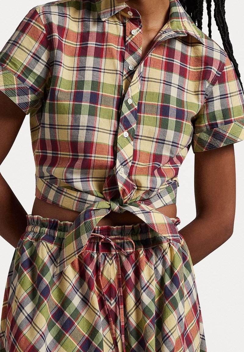 Short-sleeve plaid shirt in yellow, red, green, and blue; tied at the waist with button closure. Coordinating plaid shorts with elastic waistband.