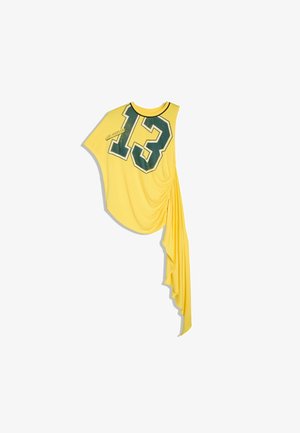 Top asymétrique jaune sans manches avec un grand "13" vert et le texte "Los Angeles", avec un tissu drapé froncé suspendu sur un côté.