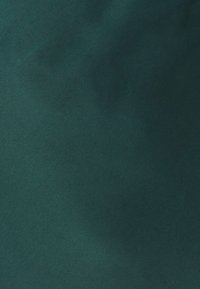 Tessuto scamosciato verde scuro con una consistenza liscia e morbida e una leggera lucentezza. Nessun motivo o dettaglio hardware visibile.