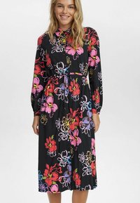 Blommig klänning med svart bakgrund, med stora rosa, röda och blå blommor. Långa ärmar, knäppning framtill och en insydd midja.