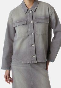 Graue Jeansjacke mit Kragen, Knopfverschluss und zwei Fronttaschen. Verfügt über eine leicht verwaschene Textur und eine lockere Passform.