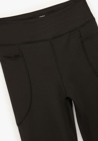 Zwarte leggings gemaakt van rekbaar materiaal met platte naden, een brede tailleband en zijzakken. Glad textuur en aansluitend ontwerp.