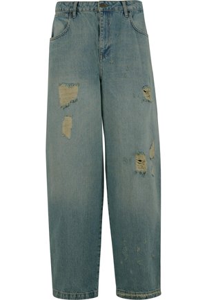 Jeans de denim azul claro con corte relajado, que presentan múltiples parches desgastados y bordes deshilachados. Diseño clásico de cinco bolsillos.
