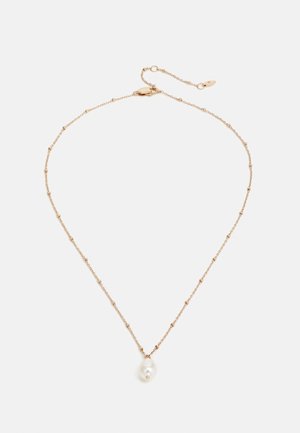 Delicate gouden ketting met kleine kralen en een enkele grote witte parel als hanger op een witte achtergrond.