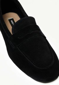 Zwarte suède instaploafers met een gladde bovenkant, decoratieve stiksels en een gevormde neus. Kenmerkt zich door een verhoogd paneel over de wreef.