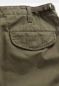 Dark olive green cotton fabric with a textured finish, featuring a single back pocket and a belt loop at the waist.
