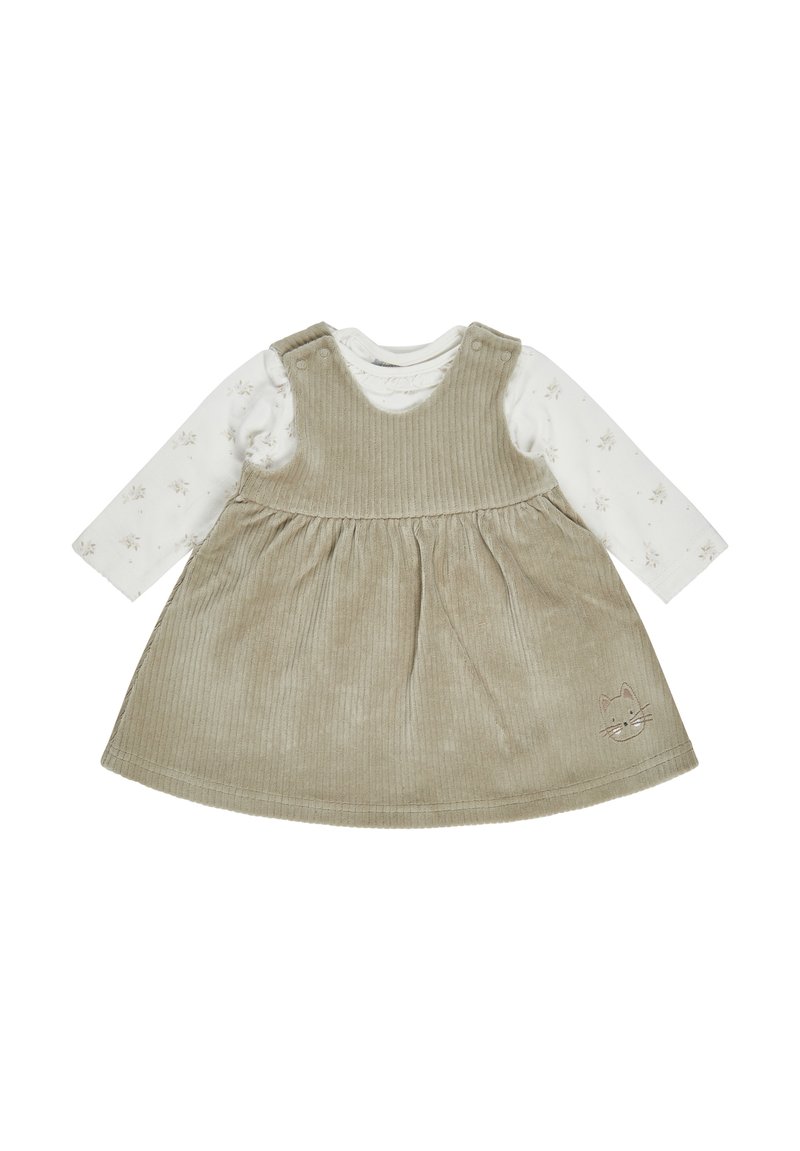 Beige Wellen-Rockkleid aus Cord, mit einem gerafften Rock und besticktem Katzenkopf, über einem weißen Langarm-Top mit Blumenmuster getragen.