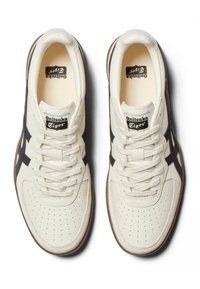 Hvide lædersneakers med sorte accenter, perforeret tåboks og kontrasterende brun gummisål. Har et vintage-logo på tungen.