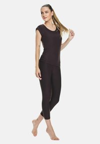 Top scurt bej cu maneci scurte și colanți capri bej, confecționați dintr-un material neted și elastic, având un guler rotund și un design slim fit.