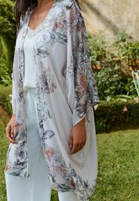 Floral kimono made of lightweight, sheer fabric; features a soft pastel color palette with large botanical prints and relaxed sleeves.