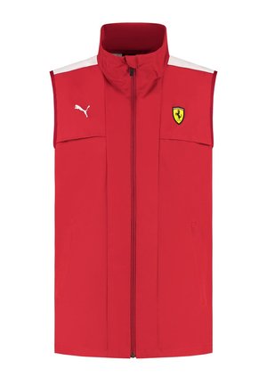 Czerwona bezrękawnik wykonany z lekkiego materiału, z wysokim kołnierzem, zamkiem błyskawicznym z przodu, białymi akcentami i logo Ferrari po lewej stronie klatki piersiowej.