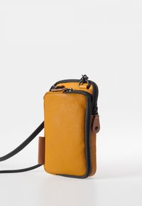 Gelbe Stoff-Crossbody-Tasche mit einem schwarzen Reißverschluss und braunen Lederelementen. Rechteckige Form, verstellbarer Träger, glatte Textur.