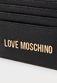 Črn usnjen denarnica z zlatim logotipom "LOVE MOSCHINO", ki je vidno prikazan. Ima več prostorov za kartice in eleganten dizajn.