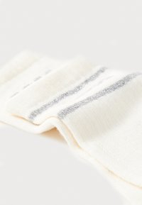 Calza bianca con strisce orizzontali argentate, texture morbida a maglia e un aspetto leggermente piegato. Nessun logo o motivo visibile.