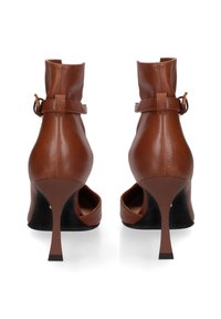Bruine leren hoge hakken met een spitse neus, enkelbandje en slanke stilettohak. Slechte textuur met een matte afwerking.