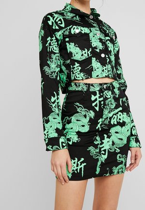 Czarny krótki komplet marynarka i spódnica z jaskrawozielonymi nadrukami smoka i azjatyckich znaków, noszony przez osobę na jednolitym tle.