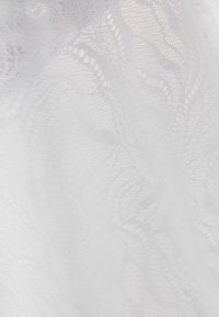 Țesătură albă transparentă cu modele delicate din dantelă florală și textură fină de plasă, drapată fin.