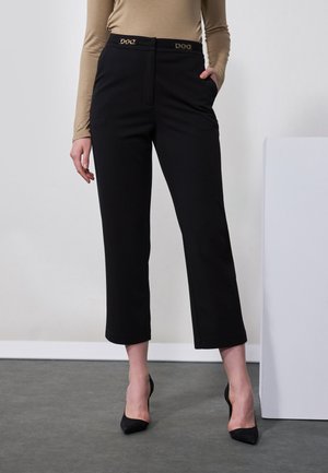 Pantalons cropped noirs ajustés avec une taille haute, présentant un subtil détail en métal doré et des poches. Tissu lisse ; coupe classique.