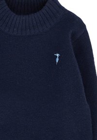 Granatowy sweter robiony na drutach z prążkowanym golfem i małym, jasnoniebieskim haftowanym logo na klatce piersiowej. Miękka textura, casualowy design.