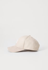 Beige Baseballcap mit einem gebogenen Schirm, aus Baumwollmaterial gefertigt. Verfügt über ein gesticktes Logo auf der Vorderseite und Belüftungsöffnungen entlang der Krone.