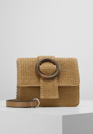 Borsa rettangolare in paglia intrecciata con grande fibbia rotonda in legno e manico in pelle beige su una superficie bianca.